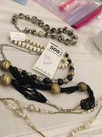Five big bead necklaces arranged on a surface with labeled tag.