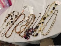 Photo of eight assorted brown palette necklaces laid out on table showing various bead types, sizes and chain links.