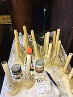 Multiple vintage cream-colored window candles with clips for mounting, arranged on a table along with a green candle and various glass holders.