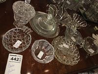Overview photo showing multiple clear glass candy dishes of various sizes and designs arranged on a surface.