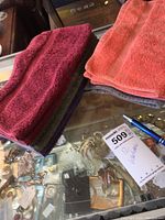 Stack of Turkish cotton washcloths in multiple colors on glass display, showing texture and fabric quality.