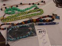 Necklaces and bracelet displayed on a table with MaxSold tag showing lot number and title.