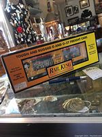 Boxed Rail King O gauge circus car with visible branding and detailed circus animal graphics through plastic box window. The box mentions die-cast metal trucks and detailed ABS plastic body.