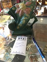 Front angled view of the green Roseville Clematis planter with pink floral relief on glass display with lot tag and pen.