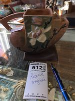 Photo of the planter showing side profile with raised magnolia flower design and part of the beige and green glaze.