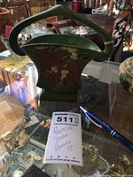 Ceramic basket with green handle and snowberry branch decoration on front.