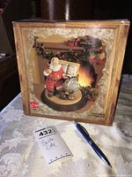Box showing Santa Coca Cola figurine with Santa, globe, and holiday decorations on a wooden base.