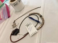 Photo showing three necklaces laid out on a white tablecloth with a blue pen for size reference; details the different styles of the necklaces including pendant and segmented beads.