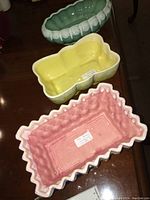 Top down view of three planters stacked, showing pink, yellow, and green colors and interior details