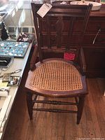 Full front view of the wooden chair showing its cane seat and wood frame