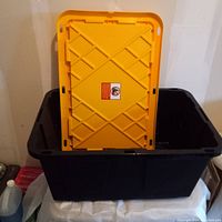 Photo showing the storage bin with the yellow lid upright inside the bin, highlighting lid design and bin depth.