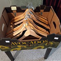 Box containing 20 natural wood finish clothes hangers with metal hooks.