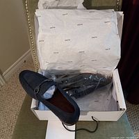 Photo showing a pair of black suede-like men's dress shoes inside an Aldo box with tissue paper wrapping the shoes.