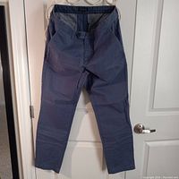 Slim fit jean pants hanging on hanger showing full front with button and zipper closure, side and belt loops visible.
