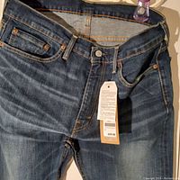 Front upper portion of Levi's jeans showing waistband, button, front pockets, and tags including price tag of $69.99