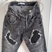 Front view close-up photo of the ripped knee detailing showing mesh backing of black ZARA jeans