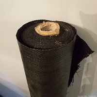 Close-up photo of the top of the rolled black woven landscape fabric showing texture and inner core.