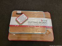Two bamboo cutting boards stacked with original packaging band labeled 'Band Cutting Board A Revolutionary Way to Prep'