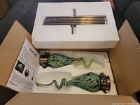 Set of two colorful glass solar garden lights in original foam packaging with instruction manual visible.