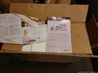 Photo of box with paperwork inside showing brand and set information.