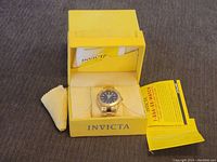 Men's Invicta automatic wristwatch inside original yellow box with papers and cleaning cloth.