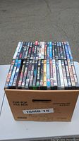 Banker box filled with 83 DVDs, showing spines of titles in protective cases, overview image to show quantity and box type.