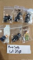 Six Lego Star Wars minifigures individually packaged in ziplock plastic bags on cardboard background, including one rebel character in green and tan and five black-clad figures.