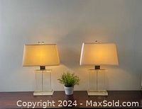 Two identical Restoration Hardware squared glass column lamps with off-white cloth shades on wooden surface against neutral wall