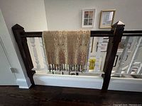 Throw blanket hanging over banister, showing pattern and tassels.