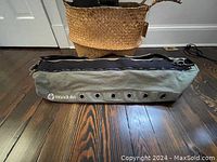 Side view of olive Manduka yoga mat carrier showing vented holes and stitching with logo