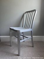 Silver metal chair with curved vertical slat back viewed at an angle