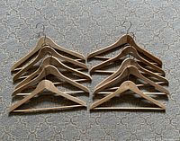 Two stacks of wooden clothes hangers arranged on carpet, showing 10 hangers but 20 included in lot.