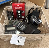 Full view of basket containing multiple electronic items including boxed Korg recorder, portable hard drive, calculators, and cassette player