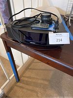 Bose Wave Music System main unit on wooden surface with remote, control pod and power cord on top