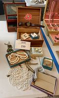 Overview of all jewelry items on display including jewelry boxes, pearl strands, earrings, watch, brooches, and gold-plated case.