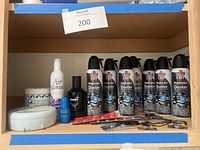 Photo showing 8 cans of Dust Off Electronics Duster, Air Scense spray bottle, Pure Linen air freshener container, Studio 35 cologne bottle, blue nail polish bottle, assorted batteries and small items