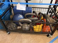 Wide shot showing multiple kettlebells in black metal cart along with a blue medicine ball and blue yoga blocks.