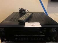 Front top-side view of Onkyo receiver amplifier with remote control placed on top, showing ventilation grilles and control panel.