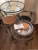 Overview of all four wrought iron plant stands grouped together showing different heights, some with plastic trays and cork pads.