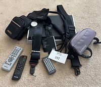 Overview of all lot contents on carpet including cases, straps, speaker case, remote controls