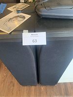 Two tall black Infinity wooden cabinet speakers side by side with seller lot tag on top.
