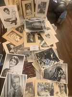 Overview of the lot showing a large number of vintage black and white photos spread out on a table, including autographed glossy photos and framed portraits.