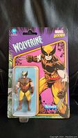Front of sealed package showing Wolverine figure in blister pack on purple background with Marvel Legends and Kenner branding