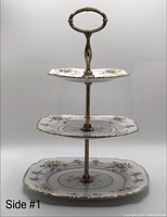 Front view of the three-tier bone china serving tray showing the square plates with floral pattern and gold-tone handle