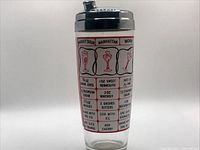 Front view of glass cocktail shaker showing printed recipe panels for Whiskey Sour, Manhattan, Bacardi, etc.