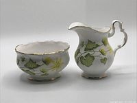 Front view of the cream and sugar set displaying ivy leaf and yellow flower pattern with gold trim