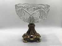 Front view of vintage crystal bowl on ornate metal pedestal base, showing cut crystal detail.