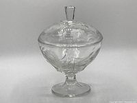 Full front view of the clear glass Hughes Cornflower pedestal candy jar with lid, showing the etched floral cornflower design and pedestal base.