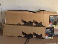 Two unopened rectangular cardboard boxes containing NOMA 4-foot colour-changing fibre optic Christmas trees, stacked horizontally.