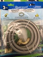 Photo of unopened Aqua-Dynamic dishwasher water supply connection kit showing coiled braided stainless steel hose and brass fittings inside clear packaging.